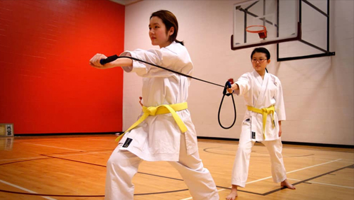 Two students performaing a karate punching drill with elestic resistance band.